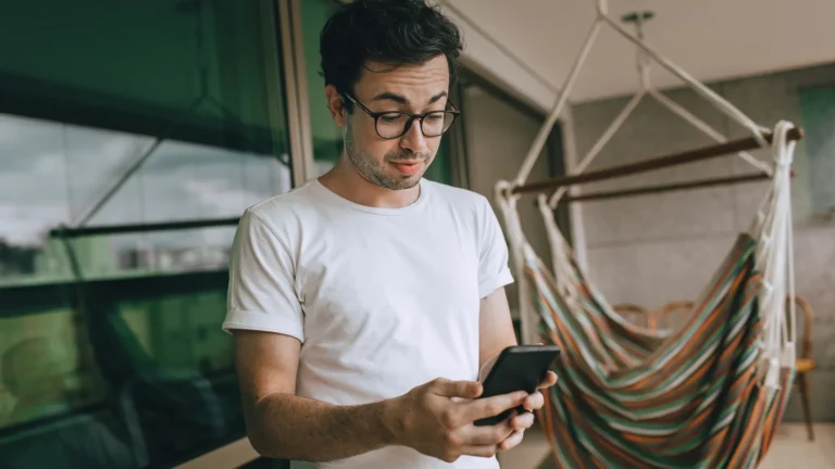 Young man in glasses reading something on his smartphone