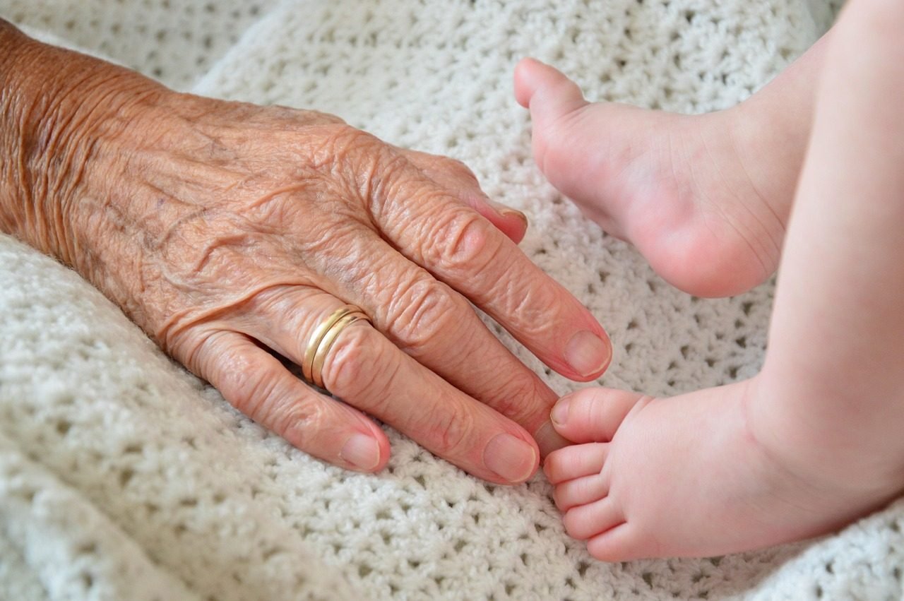 An elderly hand and a child's hand together, representing the mobility and care needs across a multi-generational group