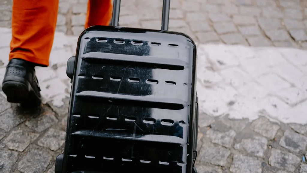 Black hard-shell suitcase being pulled over a cobbled pavement
