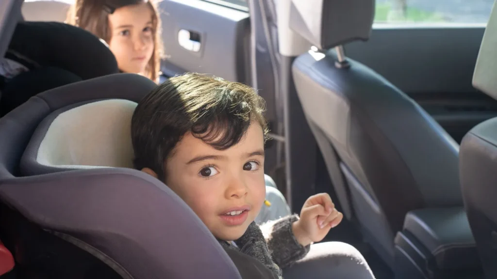 Two young children sitting in car seats in the back of a car