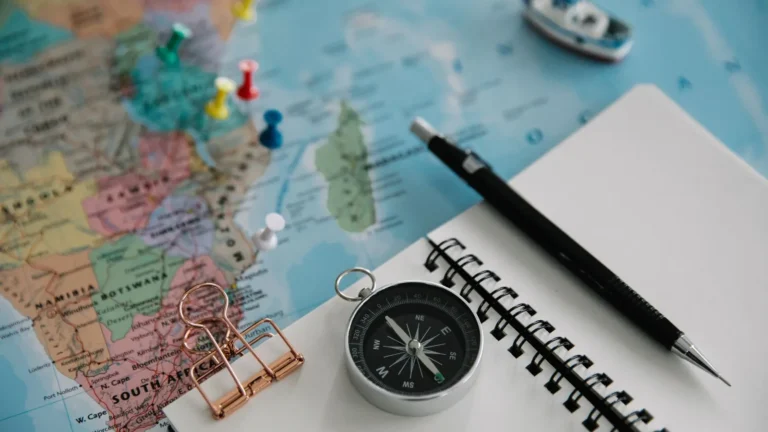 Travel planning flat lay with a map, compass, notebook and pen