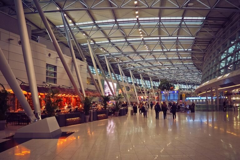 Pilgrims with luggage moving through a busy airport arrivals hall during a peak travel period