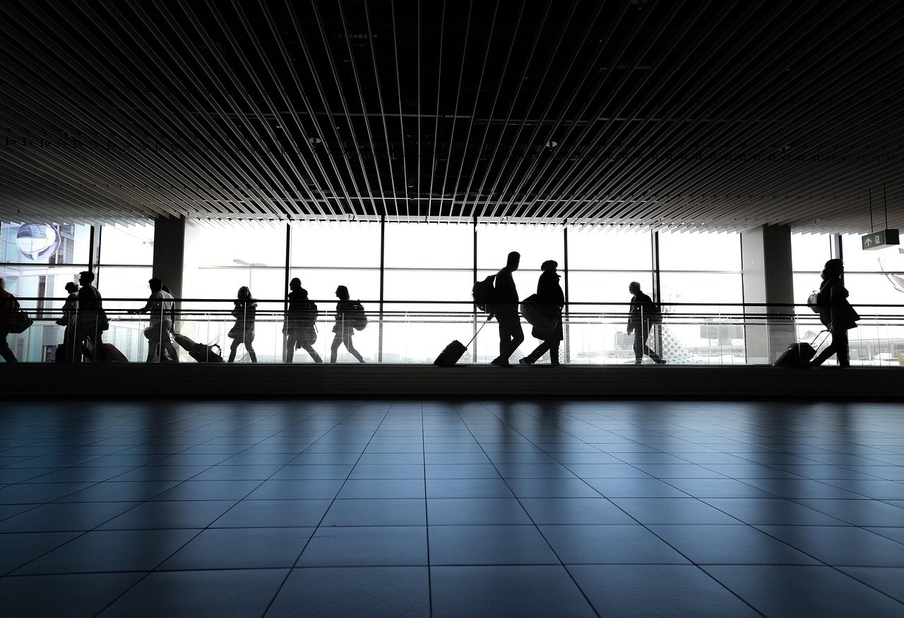 Pilgrims and luggage outside a terminal building preparing for Hajj transport