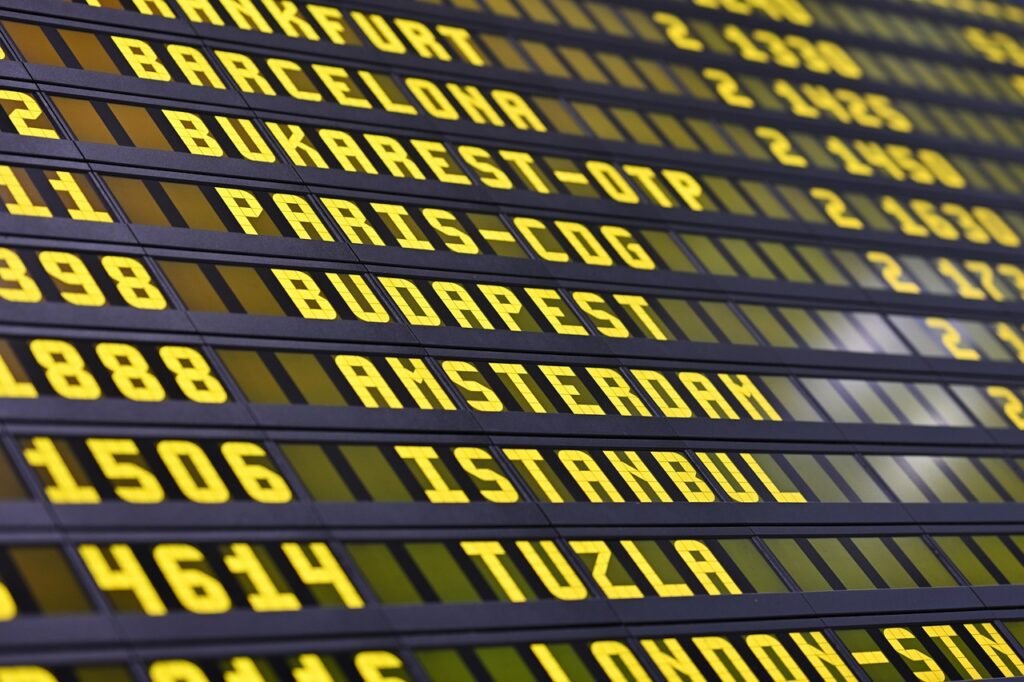 Pilgrims checking a flight departure board while planning a multi-leg journey that includes a stopover before Umrah