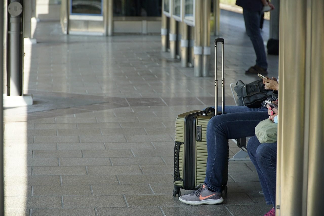 A solo pilgrim with luggage waiting for a pre-booked airport transfer