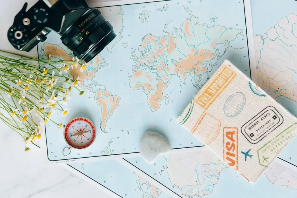 Flat lay of maps, a camera, a compass and a travel journal for planning a trip