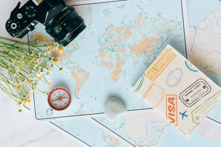 Flat lay of maps, a camera, a compass and a travel journal for planning a trip